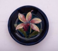 A Walter Moorcroft pottery dish tube lined in the Orchid Laelia Autumnalis pattern reserved on a