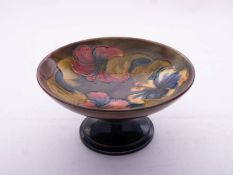 A Walter Moorcroft pottery footed dish tube lined in the Hibiscus pattern reserved on a flambé