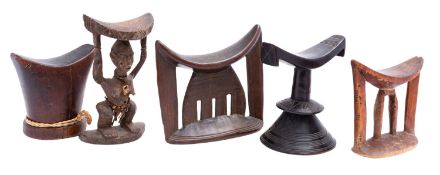 A collection of five African carved wood head rests,