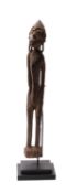A Dayak tribal carved wood male guardian figure, Borneo in traditional style with long slender body,