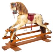 A large painted rocking horse, with leather saddle and bridle, on a pine trestle stand,