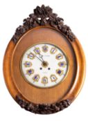 An oak oval French wall clock the eight-day duration movement striking the hours on a gong with the