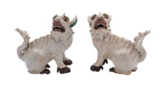 A pair of Chinese glazed stoneware models of lion dogs seated looking right and left with open jaws,