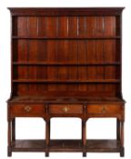 An oak dresser in the 18th Century style, the shelved superstructure with a moulded cornice,