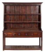 A late 18th Century oak dresser, the shelved superstructure with a moulded cornice,