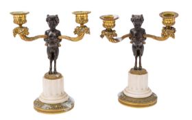 A pair of Charles X patinated and gilt bronze twin light candelabra cast as infant fauns,