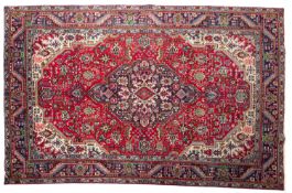 A Tabriz carpet, the red field with a central indigo geometric pole medallion,