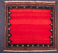 A Sofreh kelim, the plain red field within a shaded and pointed surround, 136cm x 130cm.
