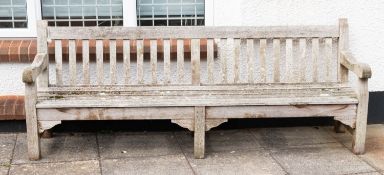 A substantial teak garden bench, modern; the backrest with straight toprail and vertical slats,