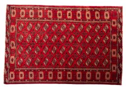 A Turkoman carpet, the red field with four rows of quartered lozenge medallions,