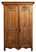 A 19th Century French pine armoire, the two panelled doors with carved decorative motifs,