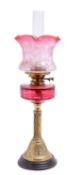 A brass and cranberry glass table oil lamp, circa 1900; the flue,