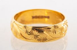 An 18ct gold wedding ring, carved all the way around with a stylised floral and foliate pattern,