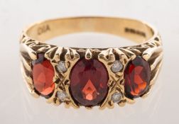 A 9ct gold garnet and diamond gypsy ring, claw set with three oval-cut garnets,