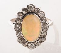 An antique opal and diamond cluster ring, collet set to the centre with an oval-cut opal cabochon,