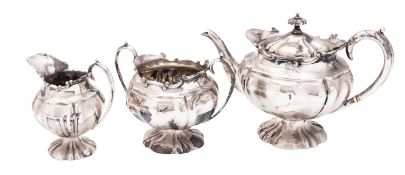 An Edwardian three-piece silver tea set, of shaped circular form, with foliate scroll borders,