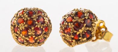 A pair of garnet stud earrings, each of bombé style, grain set with numerous circular-cut garnets,