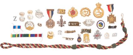 A collection of various regimental badges and lapel badges, including an NFS cap badge.
