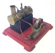 A Mamod stationery live steam engine. Mounted on a red metal base, 15cm high.
