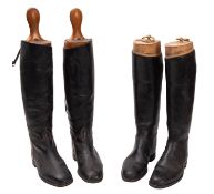 Two pairs of black leather riding boots. With wooden trees.