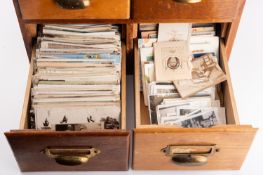 A wooden four drawer cabinet full of old postcards, greetings cars, some stamps etc.