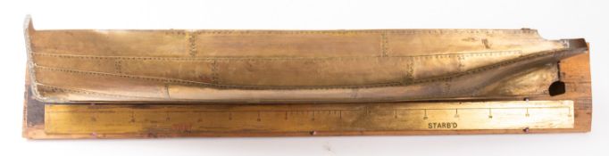 A riveted brass hull, possibly early 20th century mounted on a wooden base with brass rule beneath,