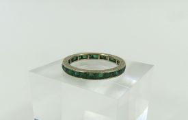 A white gold full eternity ring, the dark green st