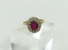 A ruby and diamond cluster ring, the oval shaped r