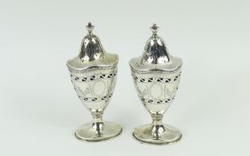 A pair of urn-shaped silver pepper pots