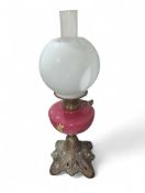 A brass oil lamp with embossed floral and scrolled