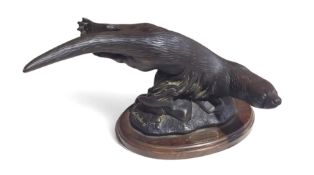 A bronzed figure of a swimming otter, on a wooden
