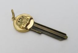 A car key with a gold rounded top, and engraved in