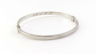 A 9ct white gold hinged oval bangle, marked ‘9K’ with