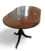 A mahogany twin pillar extendable dining table wit