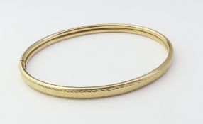 A 9ct gold fixed bangle with fine engraved decorat