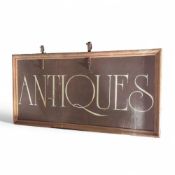 A brown painted wooden 'Antiques' sign, the text i