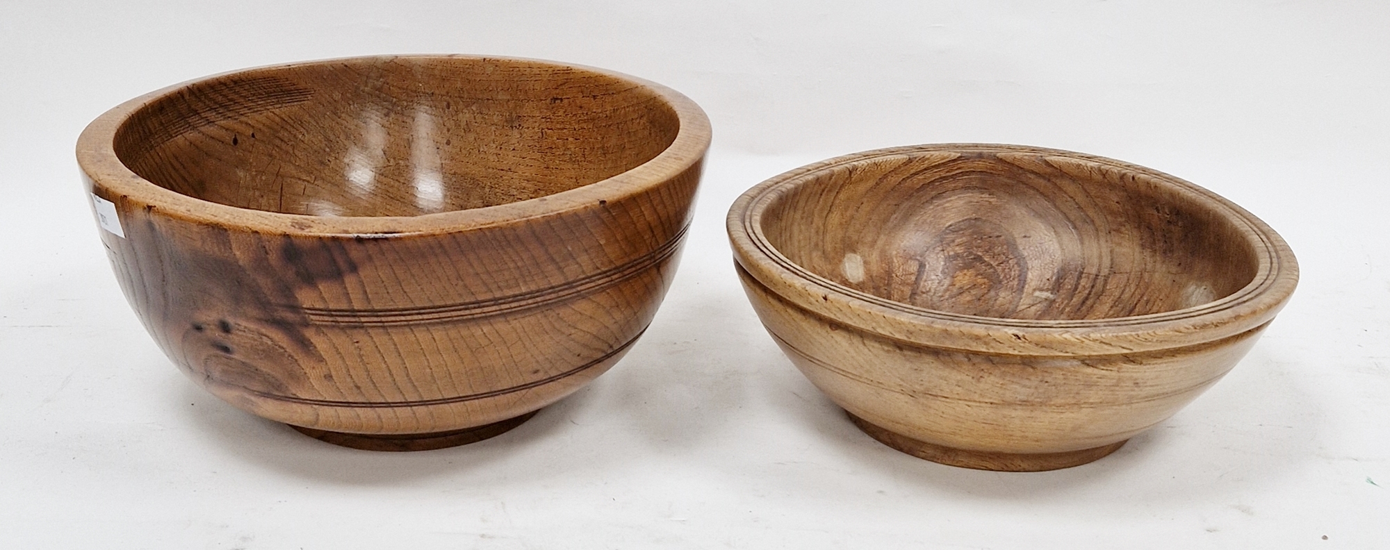 Two treen elm bowls in sizes, each turned, the first 19th/early 20th century (with repair to