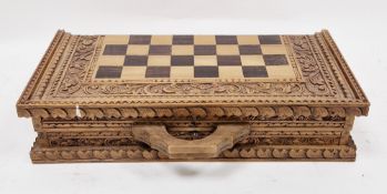 20th century Balinese carved wood chess set, the folding board carved with dense foliage, with carry