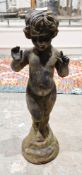 Cast iron garden ornament in the form of a standing putto, with hands raised, on a rocky mound base,