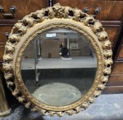 Large oval gilt-framed bevelled edge mirror with carved floral design, 92cm x 80cm