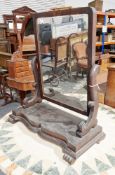 19th century mahogany swing dressing mirror, held on scrolling carved supports and a shaped platform
