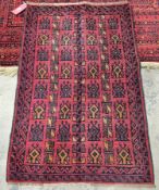 Woollen Baluchi rug with a geometric pattern on a red ground, 130cm x 85cm