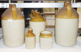 Four glazed ceramic demijohns in varying sizes (two with lids) and a similar jar (5)  Condition