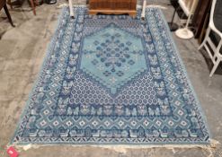 Large Tunisian blue ground rug with central floral medallion, geometric trelliswork spandrel,