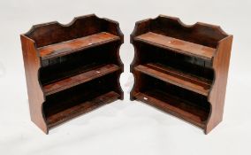 Pair of stained wooden hanging wall shelves, each having shaped tops, shaped sides and three