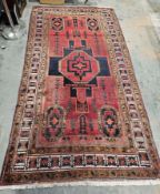 Large Eastern red ground rug with central geometric medallion, four elephant foot guls and
