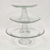 Three 20th century graduating glass cake stands or comports in sizes, each with upturned rim, on
