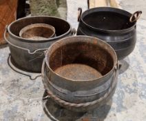 Two cast iron cooking cauldrons, a metal cauldron and a cast iron oval cooking pot, largest cauldron