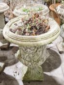 Two similar composite stone garden urns of campana form, each with moulded decoration of Roman