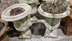 Two similar composite stone garden urns of campana form, each with moulded decoration of Roman